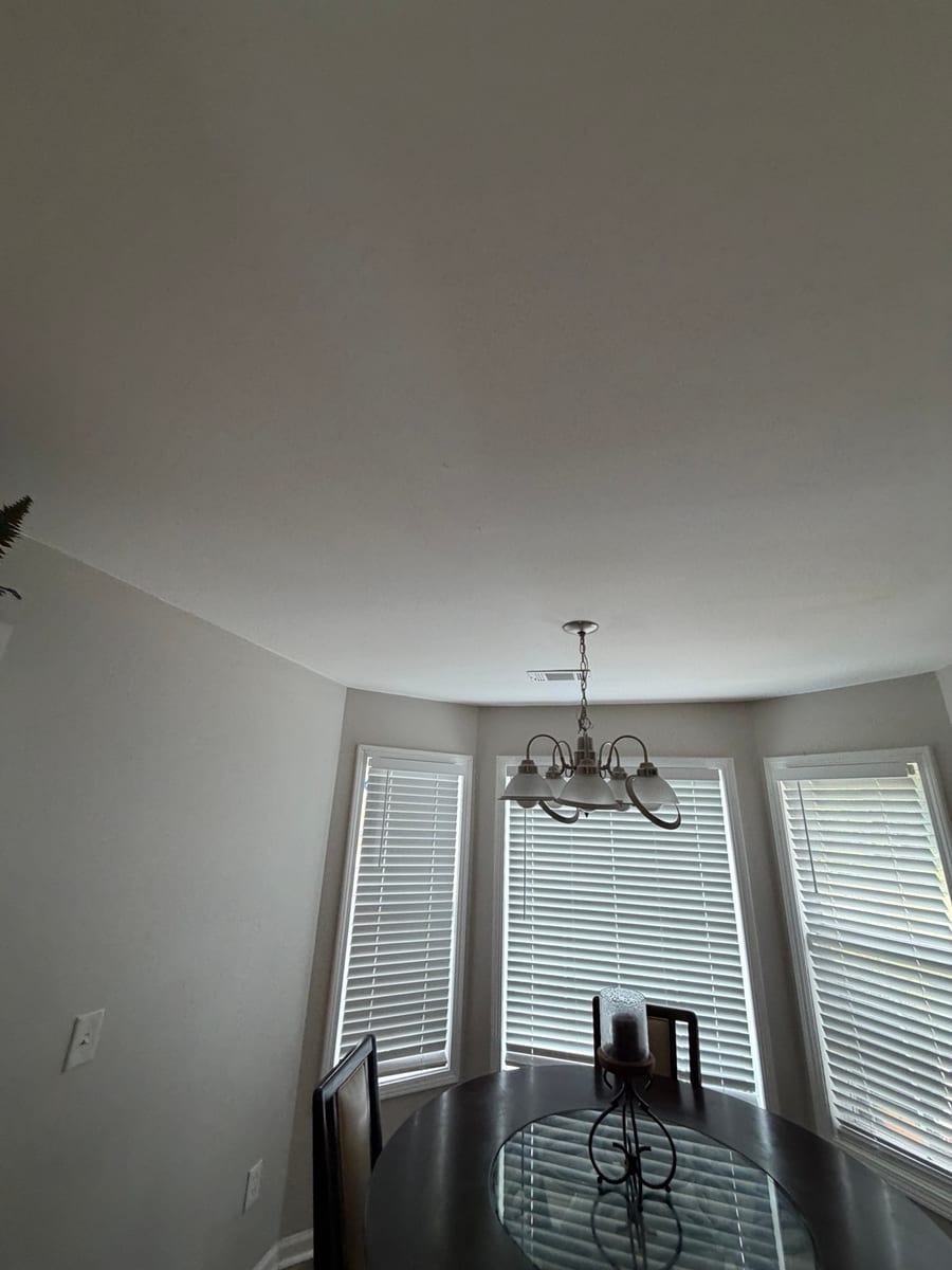 Light interior ceiling and walls above a dining area with bay windows
